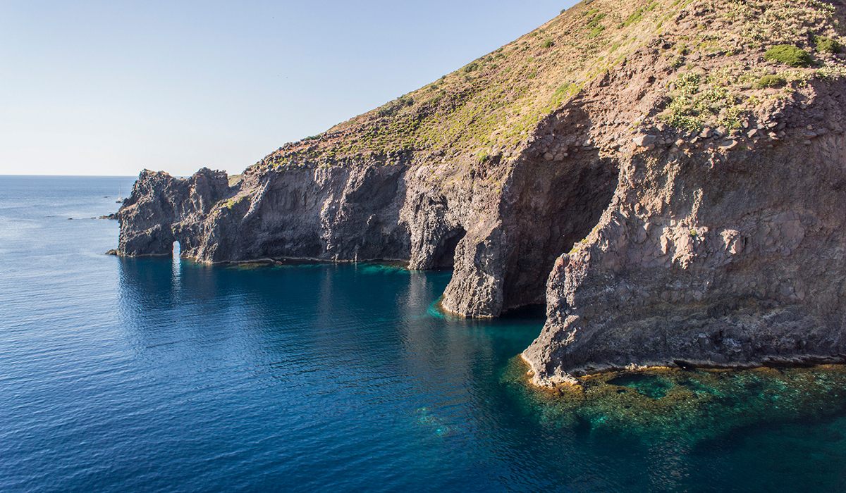 Scogliere vulcaniche e mare blu presso la Grotta del Bue Marino a Filicudi